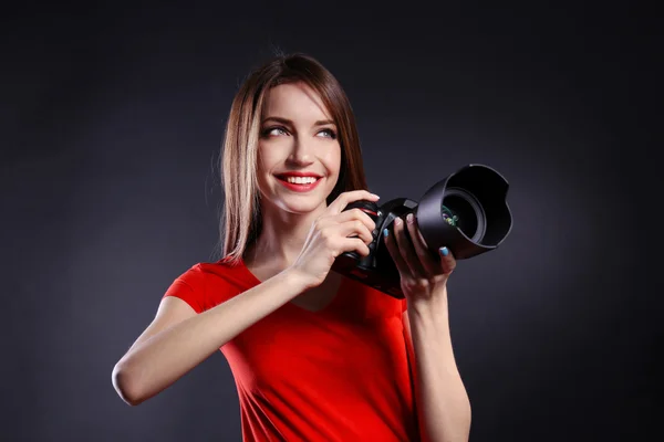 Joven fotógrafa tomando fotos sobre fondo negro — Foto de Stock