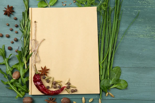 Öppna receptbok med färska örter och kryddor på trä bakgrund — Stockfoto