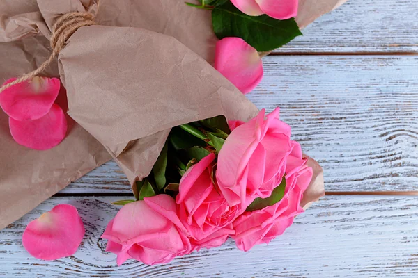 Krásné růžové růže na dřevěný stůl s pergamenem, detail — Stock fotografie