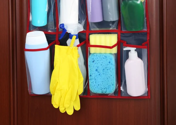 Diferiți detergenți în geanta agățată ușă din lemn — Fotografie, imagine de stoc
