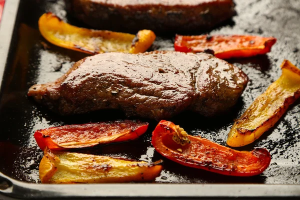 Composition with tasty roasted meat and sliced pepper on pan, tomatoes and rosemary sprigs close-up — Stock Photo, Image