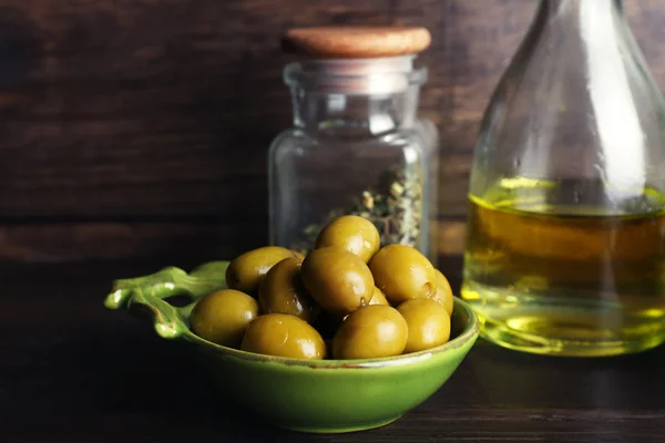 Olive con olio su tavola su fondo legno — Foto Stock