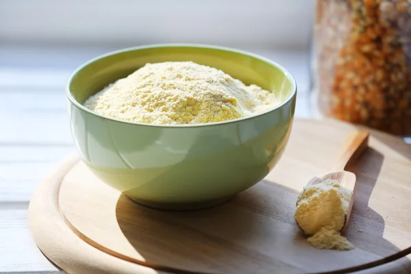 Flour in bowl with scoop on cutting board near glass bottle of corn on wooden planks background — Stock Photo, Image