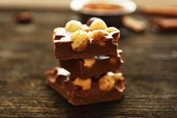 Stack of chocolate with nuts on wooden table, closeup — Stock Photo, Image