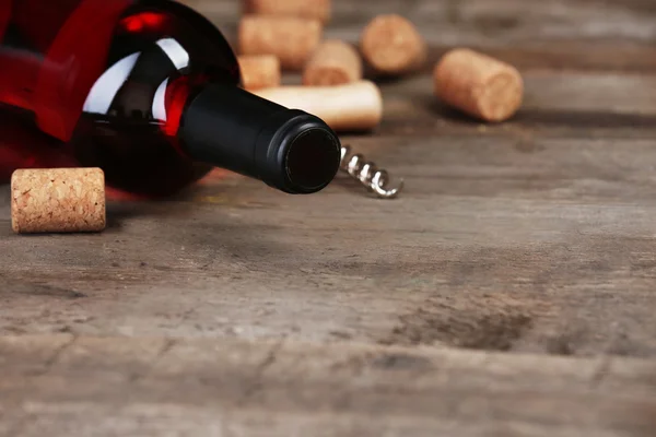 Стеклянная бутылка вина с пробками и штопор на деревянном фоне стола — стоковое фото
