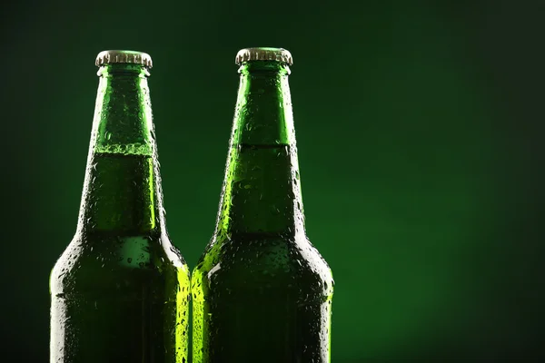 Botellas de vidrio de cerveza sobre fondo verde oscuro —  Fotos de Stock