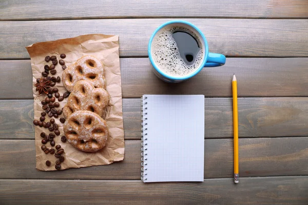 Tasse de café avec biscuits frais et feuille de papier vierge sur table en bois, vue sur le dessus — Photo