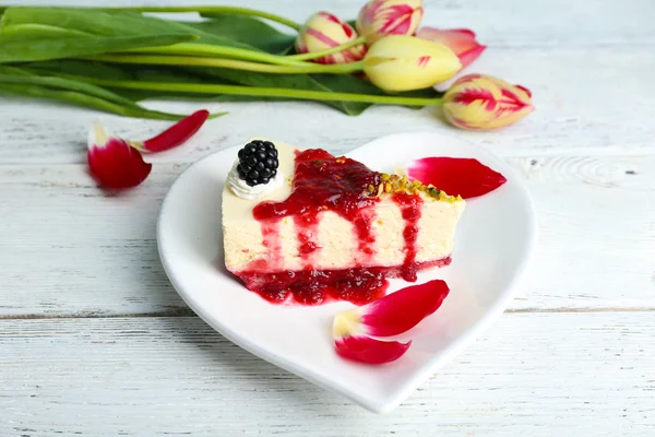 Sabroso pedazo de pastel de queso con salsa de bayas en el plato en la mesa de cerca —  Fotos de Stock