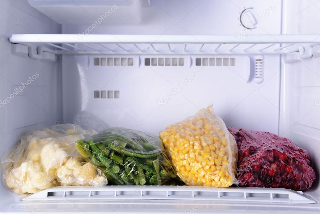 Frozen berries and vegetables in bags in freezer close up