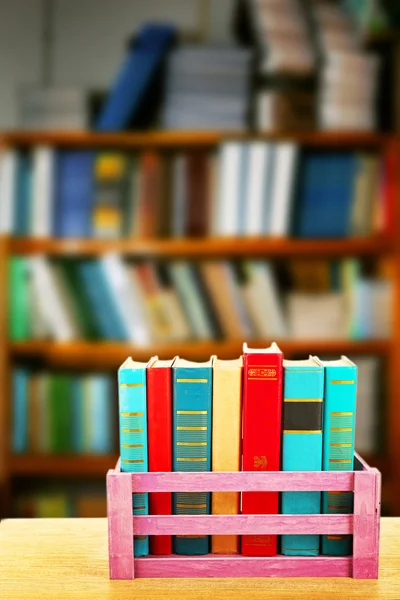 Buku-buku di peti kayu pada latar belakang rak buku — Stok Foto