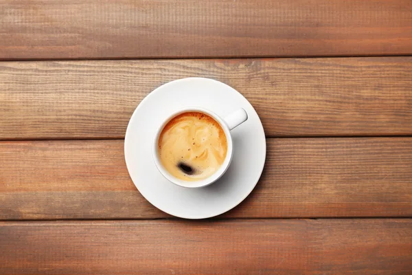 Šálek kávy na dřevěném stole, pohled shora — Stock fotografie