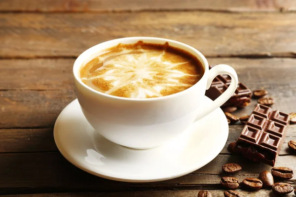 Kopje koffie latte kunst met granen en chocolade op houten achtergrond — Stockfoto
