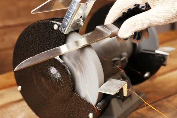 包丁研ぎ器と木製のテーブル、クローズ アップの刃を持つ手 — ストック写真
