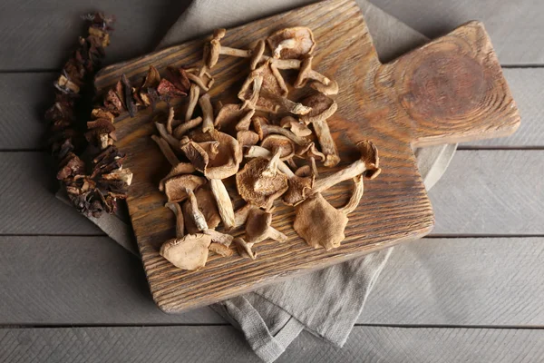 Gedroogde champignons op snijplank op houten achtergrond — Stockfoto