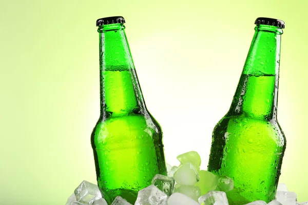 Glazen flessen bier in ijsblokjes — Stockfoto