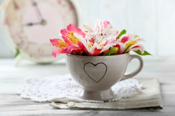 Schöne Blumen in Tasse, auf Holzgrund — Stockfoto