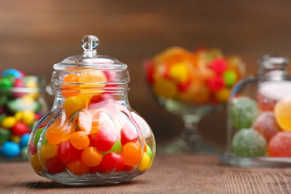 Kleurrijke snoepjes in potten op tafel op houten achtergrond — Stockfoto