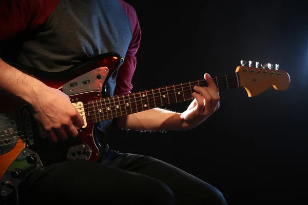 Young man playing on electric guitar on dark background — Stock Photo, Image