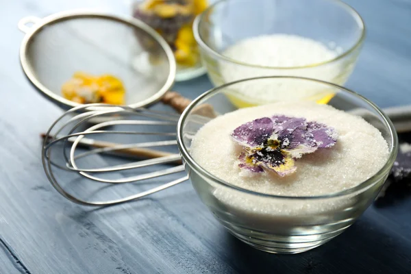 Elaboración de flores violetas confitadas con claras de huevo y azúcar, sobre fondo de madera de color — Foto de Stock