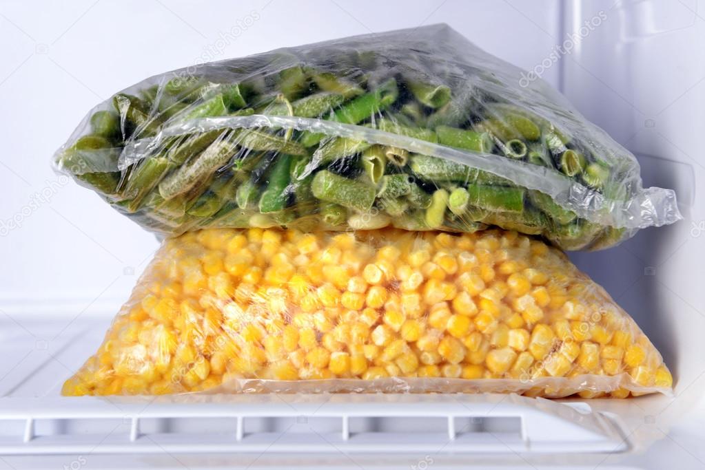Frozen vegetables in bags in freezer close up