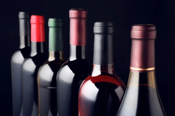 Bouteilles de vin en rangée sur fond noir — Photo