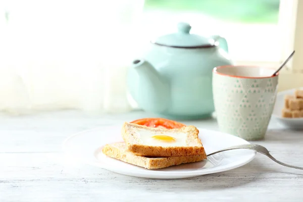 Scrambled egg with bread on plate with cup of tea on bright background — Stock Photo, Image