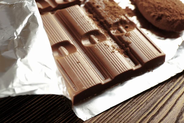 Bar of chocolate with cocoa on foil, closeup — Stock Photo, Image