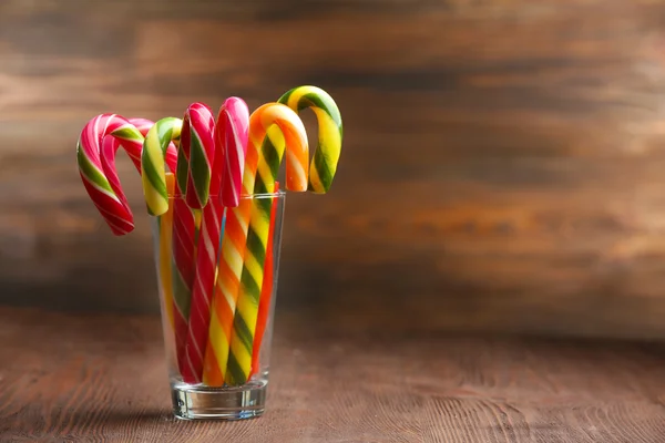 Kleurrijke snoep stokken in glas op tafel op houten achtergrond — Stockfoto