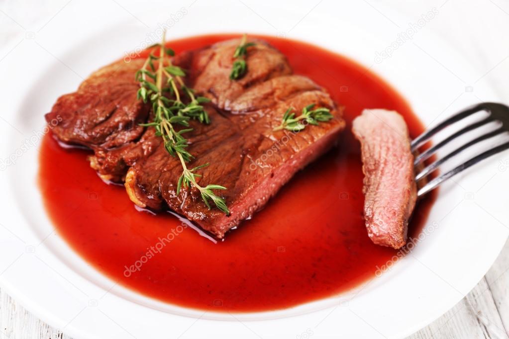 Steak with wine sauce and herbs on plate close up