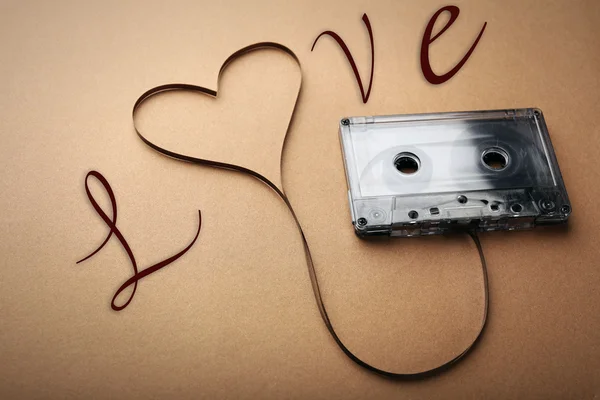 Cassette de audio con cinta magnética en forma de corazón sobre fondo marrón — Foto de Stock