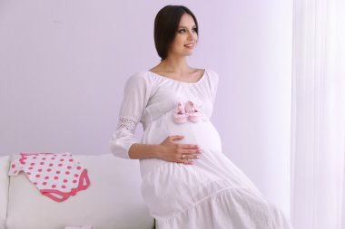 Beyaz duvar arka koltukta oturan bebek patik ile hamile kadın