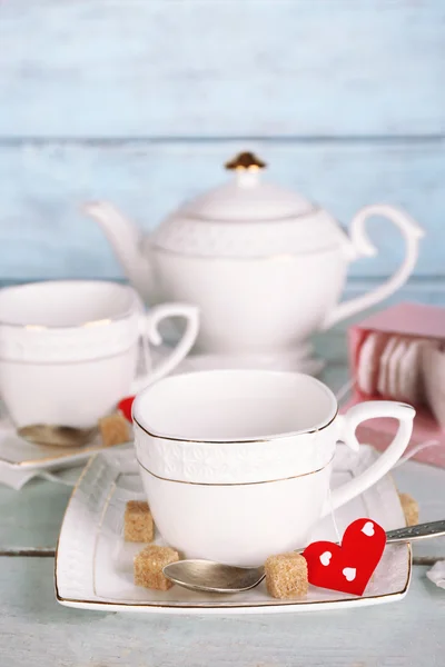 Woman pouring hot tea from teapot into cup wooden background — Stock Fotó