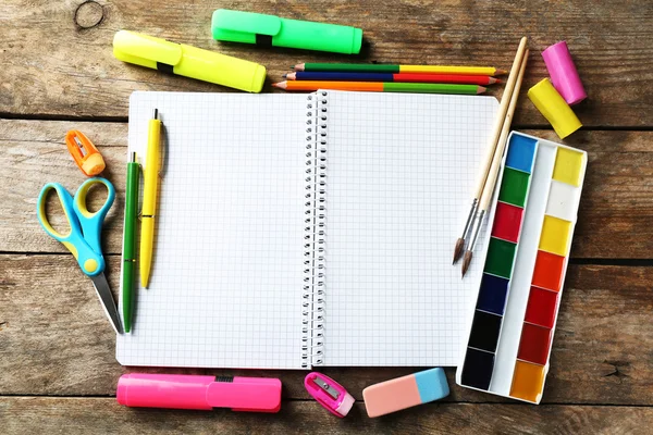 Notebook en heldere school briefpapier op oude houten tafel — Stockfoto