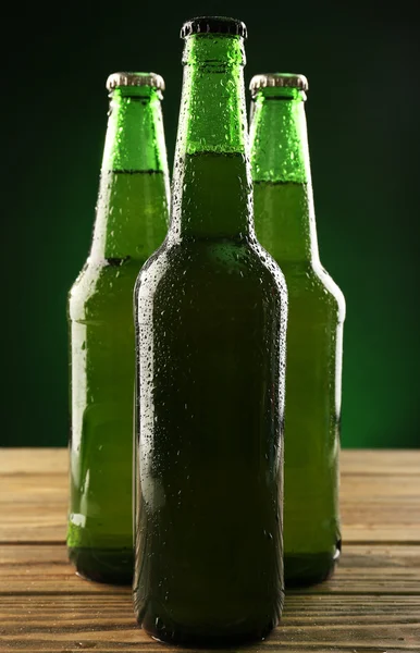 Glazen flessen bier op donkere groene achtergrond — Stockfoto