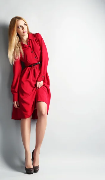 Modelo joven expresivo en vestido rojo sobre fondo gris —  Fotos de Stock