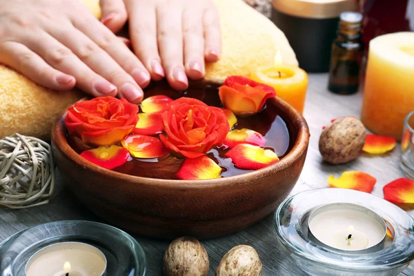 Mains féminines avec bol d'eau de spa aromatique sur table en bois, gros plan — Photo