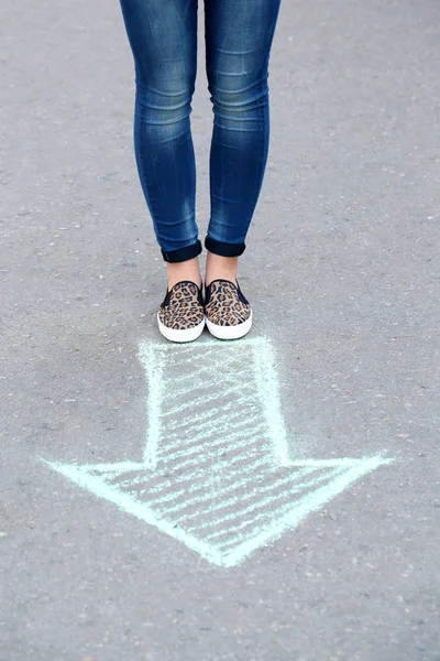 Női láb és a rajz nyíl a járdán háttér — Stock Fotó