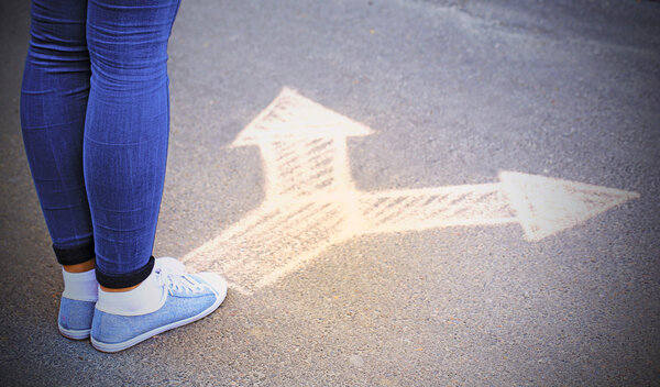 Женские ноги и рисование стрелок на фоне тротуара
