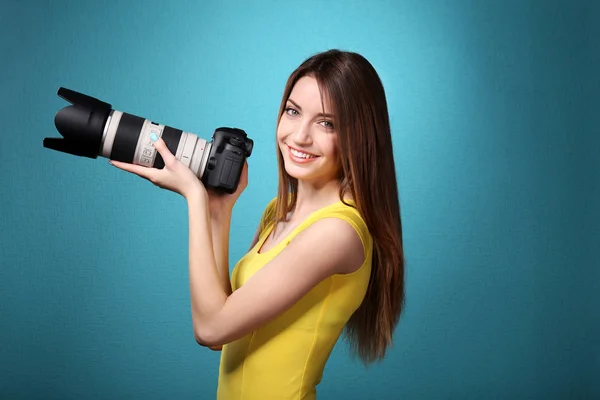 Młoda kobieta fotograf robienia zdjęć na niebieskim tle — Zdjęcie stockowe