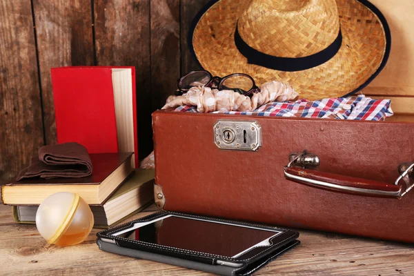 Packing suitcase for trip on wooden background — Stock Photo, Image