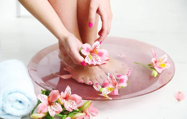 Woman washing beautiful legs in bowl, on light background. Spa procedure concept — Stock Photo, Image