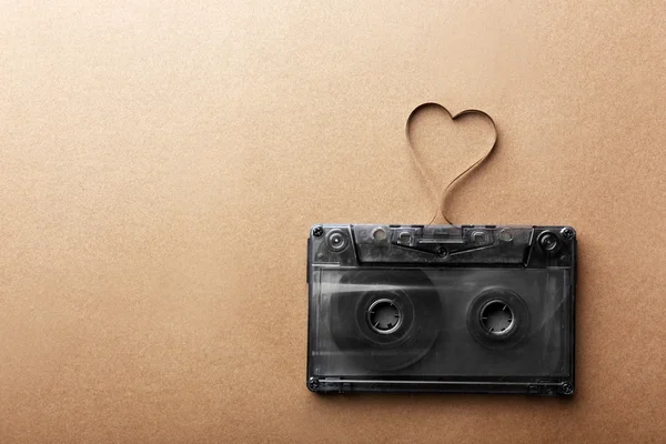 Audiocassetta con nastro magnetico a forma di cuore su sfondo marrone — Foto Stock