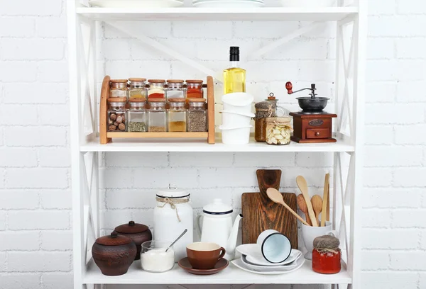 Кухонные полки с посудой на фоне белой кирпичной стены — стоковое фото