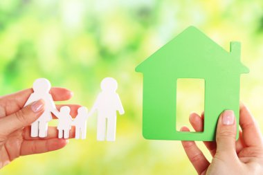 konut ve kağıt aile modelinin parlak arka planda tutan eller