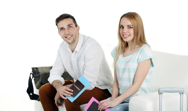 Портрет молодой счастливой пары с багажом, сидящей на диване. Изолированные на белом — стоковое фото
