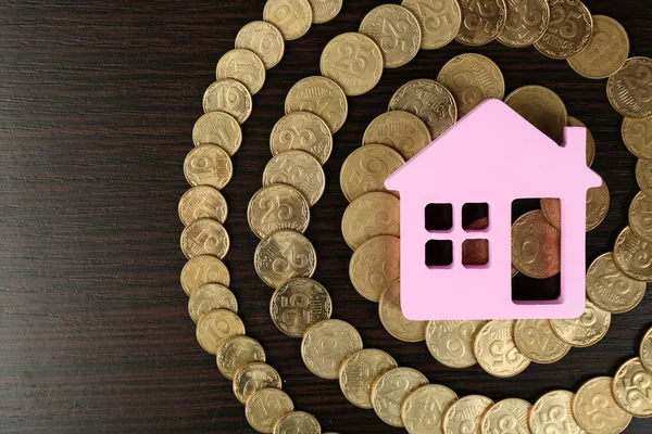 Model of house with coins on wooden table, closeup — Stock Photo, Image