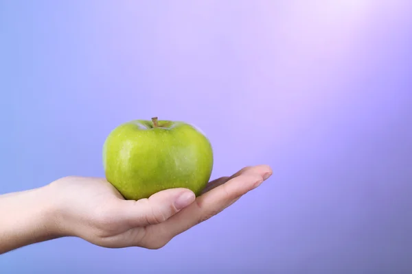 Vrouwelijke hand met apple op kleurrijke achtergrond — Stockfoto
