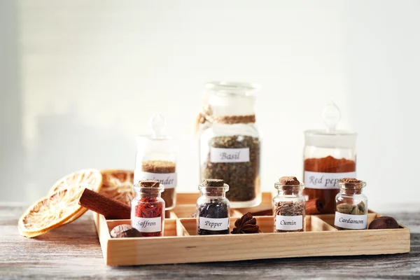 Assortment of spices in glass bottles in box, on light background — Stock Photo, Image