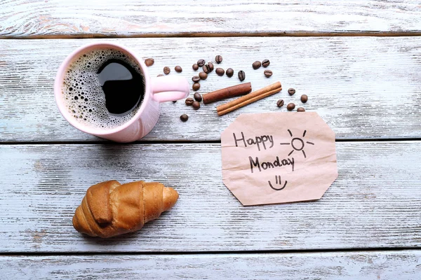 Kopp kaffe med färsk croissant och glad måndag massage på träbord, ovanifrån — Stockfoto