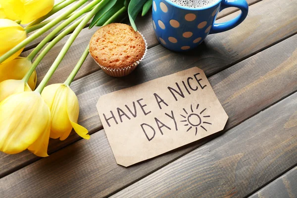 Tasse de café avec cupcake frais, tulipes et avoir une belle journée massage sur fond de bois — Photo